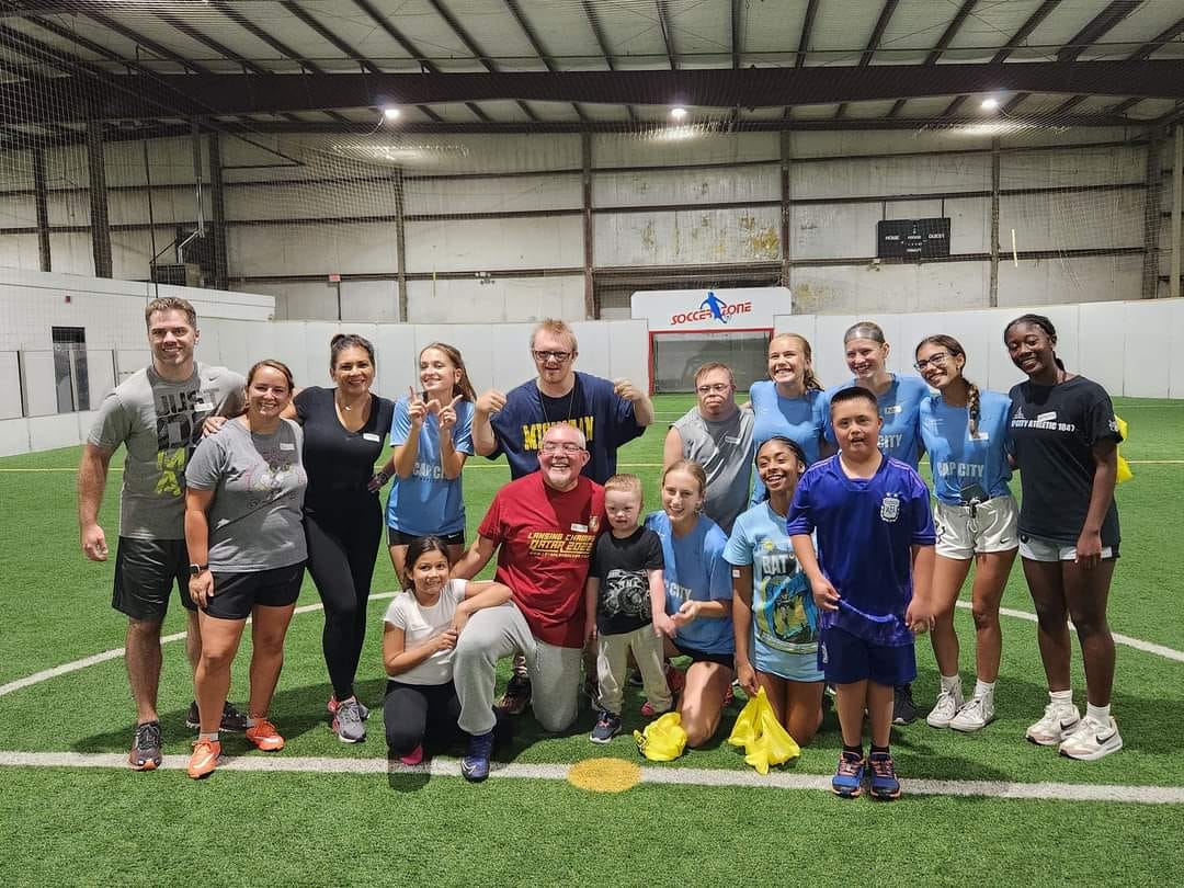 A group posed together on an indoor soccer field.